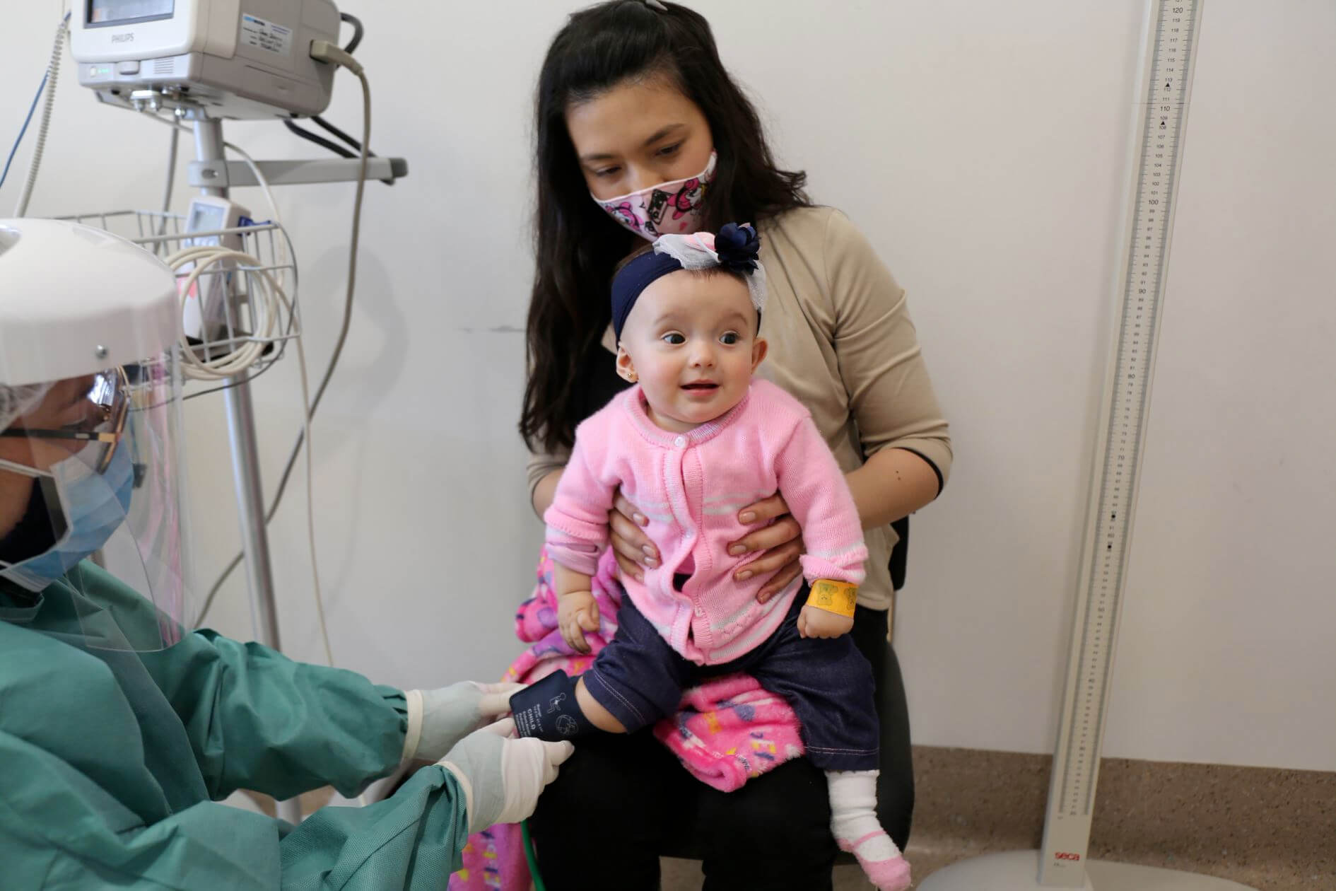 Médico de LaCardio tomando signos vitales a una bebé mientras está con su madre en consulta pediátrica, enfocada en la atención cardiovascular infantil. - LaCardio