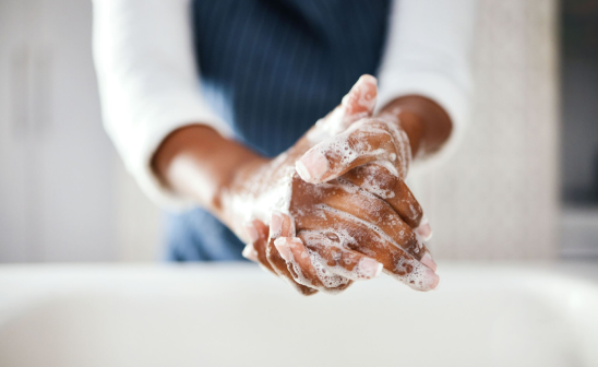 Persona lavándose las manos con jabón en un fregadero, mostrando la importancia de la higiene y el cuidado personal. - w-100